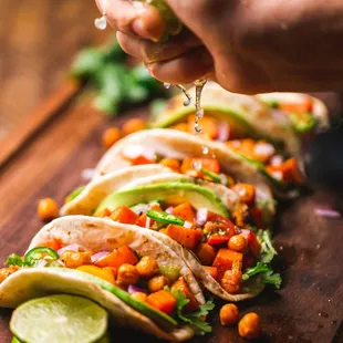 a hand sprinkling a lime on a tortilla