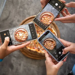 a group of people taking a picture of a pizza