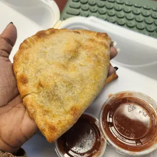 a hand holding a piece of empanada