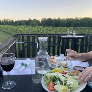 a woman eating a salad and a glass of wine