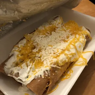 Rolled tacos, sour cream and cheese.