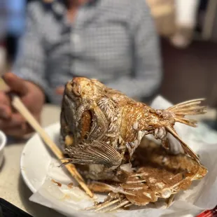 a man eating a fish with chopsticks