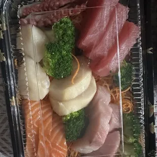 a variety of sashimis in a plastic container