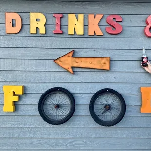 a woman standing in front of a sign that says drinks and food