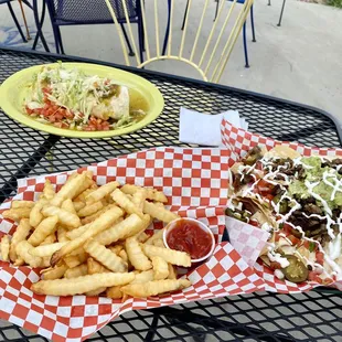 two plates of tacos and fries