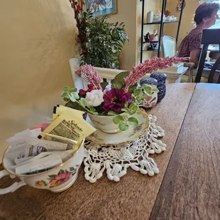 Cute tea cup holding flowers and one with sugar packets