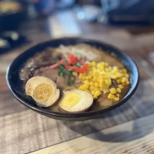 a bowl of ramen with a boiled egg and corn