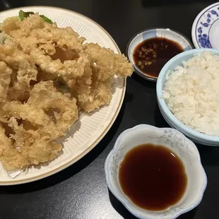 a plate of fried squid with rice and sauce