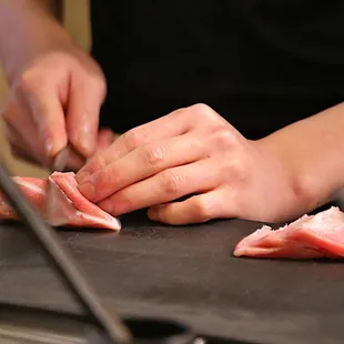a person chopping meat on a cutting board