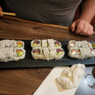 a man holding chopsticks over a plate of sushi