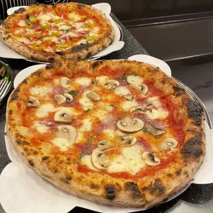 two pizzas on plates on a counter
