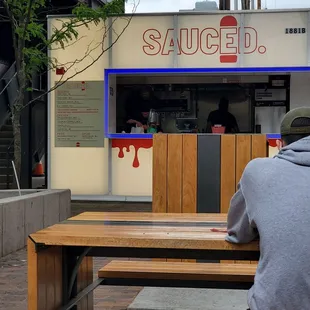 a man sitting on a bench in front of a restaurant