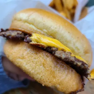 a hand holding a hamburger with a side of fries