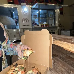 a woman holding a box of pizza