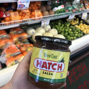 a hand holding a jar of hatch salsa