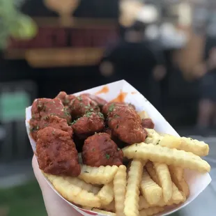 a hand holding a basket of food