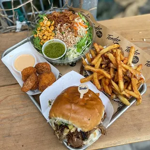 The pineapple-teriyaki pulled pork sandwich, French fries, the nutty cilantro salad, and Impossible chick&apos;n nugz. All vegan!