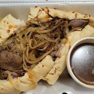 American dip with au jus with grilled onions on an onion bread roll.