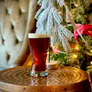 a glass of beer on a table in front of a christmas tree