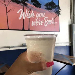 a hand holding a plastic cup of beer