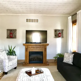Living room with a couch, sofa, ottoman, chair and electric fire place.