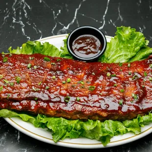 a plate of ribs with lettuce and sauce