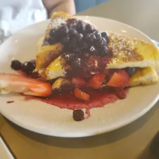 Stuffed  French toast with fresh  strawberries and blueberries and whip cream.
