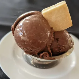 a scoop of chocolate ice cream with a biscuit on top