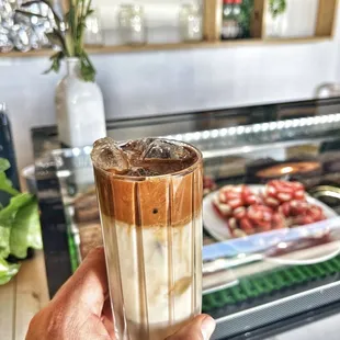 a hand holding a glass of iced coffee