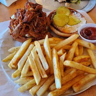 a plate of french fries and a pulled pork sandwich