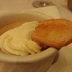 a bowl of soup with whipped cream and a biscuit