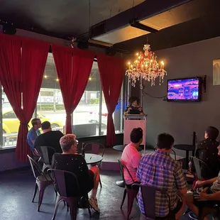 a group of people sitting in a room with red drapes