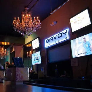 a bar with a chandelier and televisions