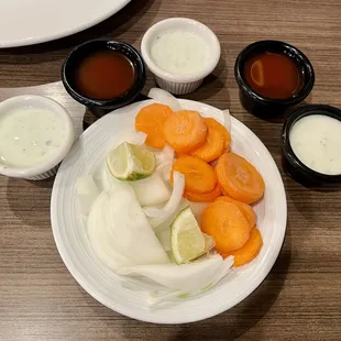 a plate of carrots, onions, and sauces