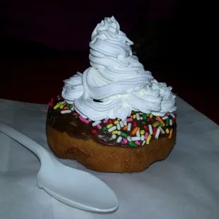 a chocolate donut with whipped cream and sprinkles