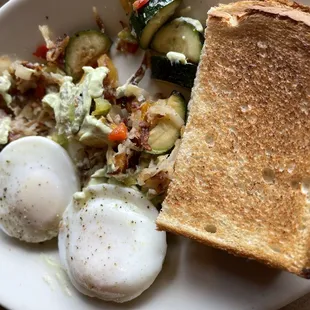 a plate of eggs, bread, and vegetables