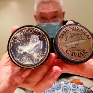 a man in a face mask holding two tins of shaving