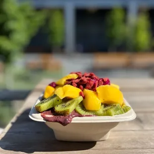 a bowl of fruit on a wooden table