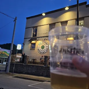 a person holding a beer in front of a building