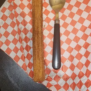 Churro. I put it next to a large spoon to show its size. It's really good with lots of cinnamon sugar. I would order again