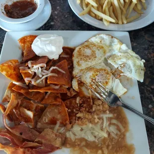 Chilaquiles en salsa Roja, huevos al gusto, tocino y frijolitos.  Postre muy delicioso.