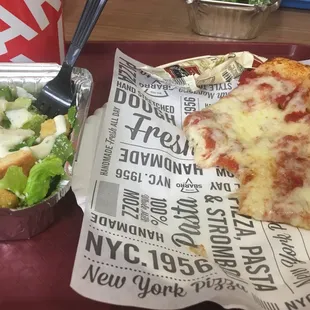 a pizza and salad on a tray