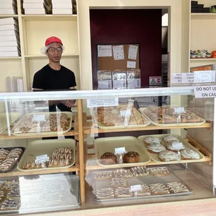 a man behind the counter of a bakery