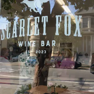 the reflection of a tree in the window of a wine bar