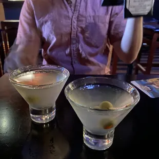 a man sitting at a table with two martinis