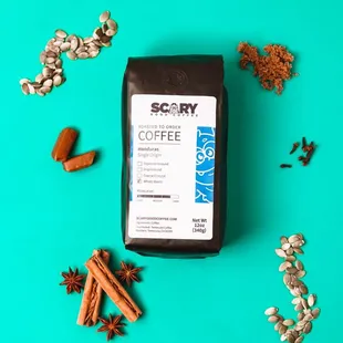 a bag of coffee surrounded by cinnamons and cloves