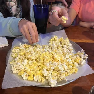 a woman scooping popcorn into a bowl