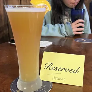 a woman sitting at a table with a glass of beer
