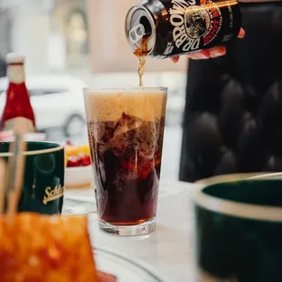 a person pouring a drink into a glass