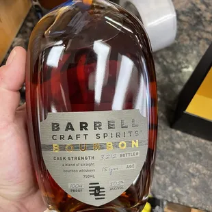 a hand holding a bottle of bourbon